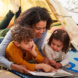 Single Mother Reading With Son And Daughter In Den In Bedroom At Home Single Mother Reading With Son And Daughter In Den In Bedroom At Home