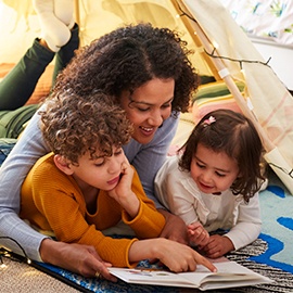 Single Mother Reading With Son And Daughter In Den In Bedroom At Home