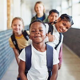 Portrait of a group of young children standing in a line in the hallway of a school