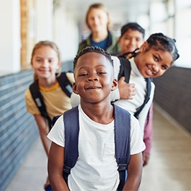 Portrait of a group of young children standing in a line in the hallway of a school