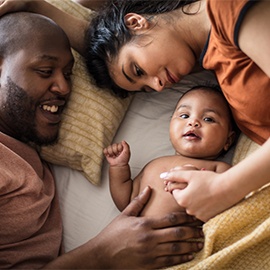 Family bonding time. African American parents with daughter on bed.