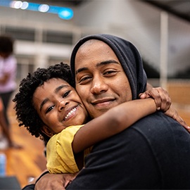 Portrait of father and daughter embracing at a community center