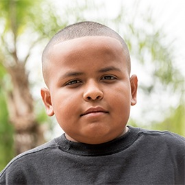 Serious Hispanic little boy looking at the camera embracing