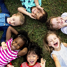 Group of kindergarten kids lying on the grass at park and relax with smiling