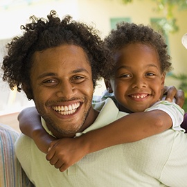 Man piggybacking young boy with two older men standing beside him